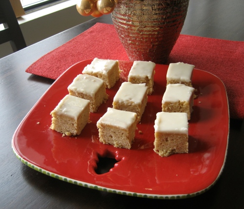 Nine maple squares on a red christmas plate with a gold plant pot in the background