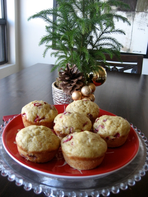 Six Christmas Morning Cranberry Muffins on a red plate with a Christmas plant in the background